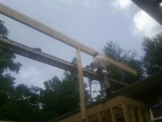 Carpenter setting a ridge beam over a new addition frame — Ice Dam Removal by Roofing Brothers in Saint Regis