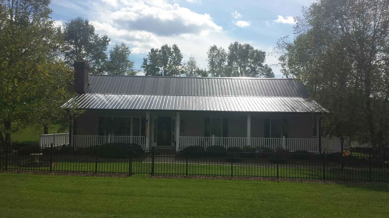 Gray metal roof on a brick ranch with a full width front porch — Gutter Guard Installation work by our crew in Saint Regis