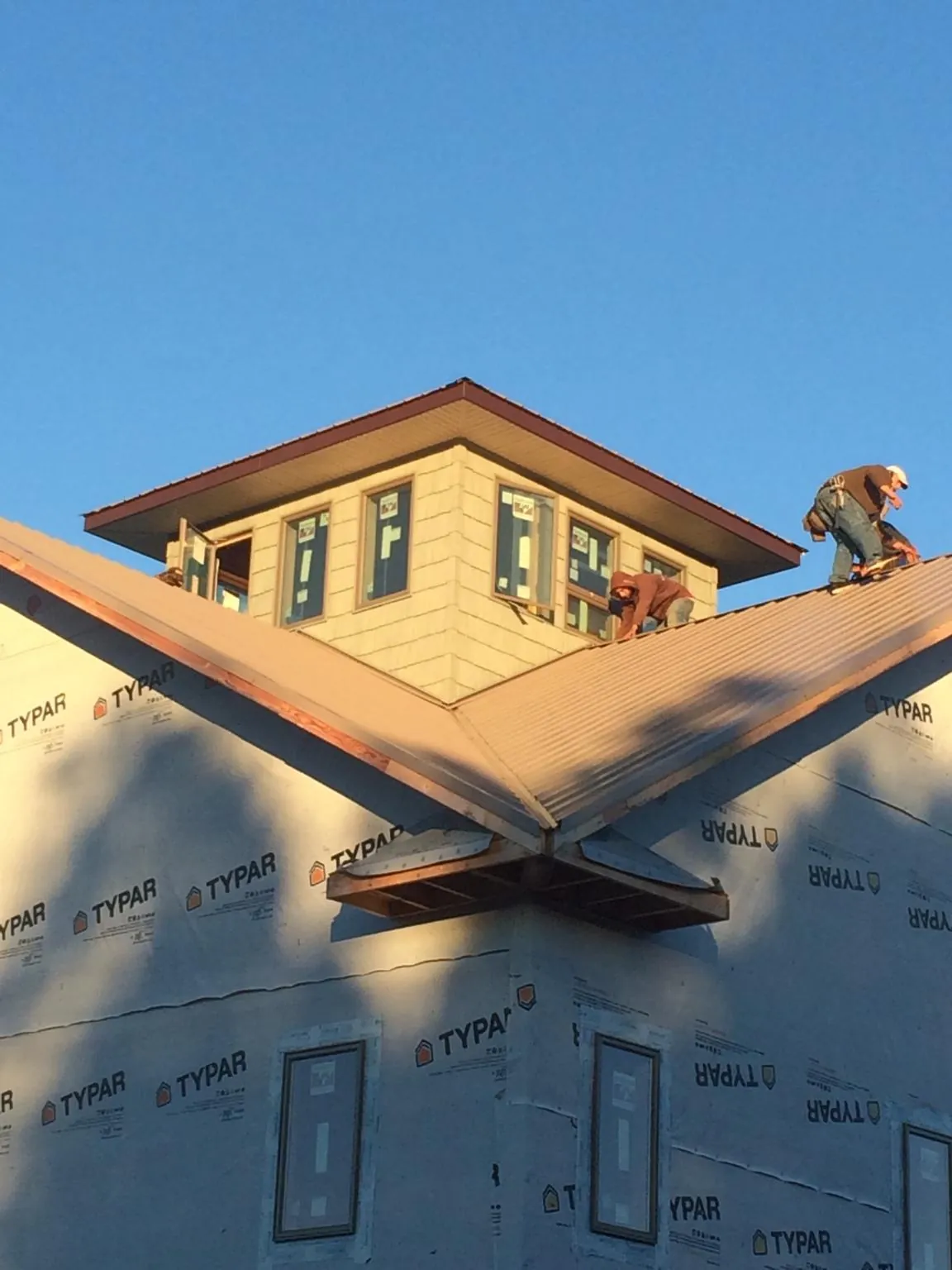 Roofers working around a rooftop cupola on a new metal roof at sunset — Roof Waterproofing in Saint Regis by Roofing Brothers